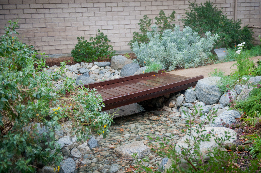This is an example of an expansive traditional courtyard shaded xeriscape for winter in Los Angeles with a garden path and decomposed granite.