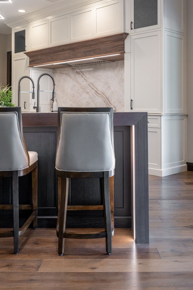 Open concept kitchen - large transitional medium tone wood floor and brown floor open concept kitchen idea with a double-bowl sink, flat-panel cabinets, white cabinets, quartzite countertops, beige backsplash, stainless steel appliances, an island and beige countertops