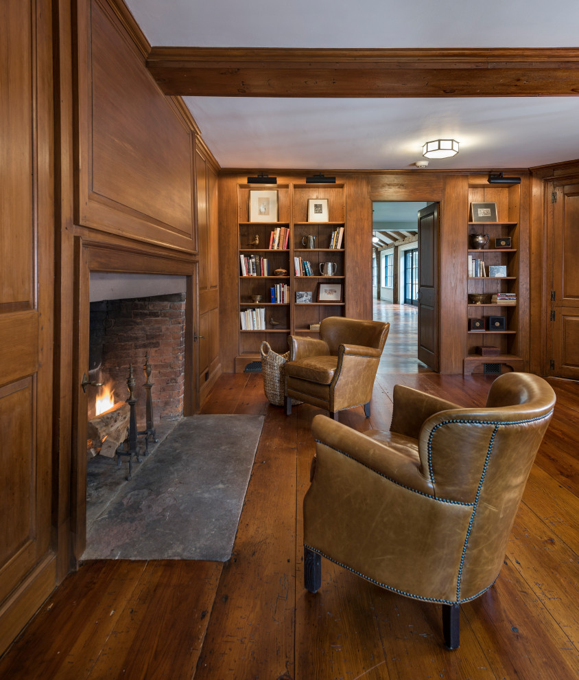 This is an example of an expansive country open concept living room in Boston with a library, medium hardwood floors, a standard fireplace, a wood fireplace surround, exposed beam and panelled walls.