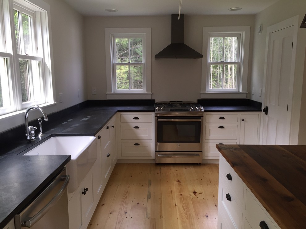 Design ideas for a mid-sized transitional l-shaped eat-in kitchen in Burlington with a farmhouse sink, shaker cabinets, white cabinets, soapstone benchtops, stainless steel appliances, light hardwood floors and with island.