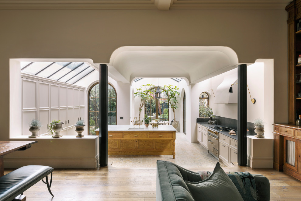 Große Wohnküche mit bunten Elektrogeräten, Keramikboden, Kücheninsel und beigem Boden in London