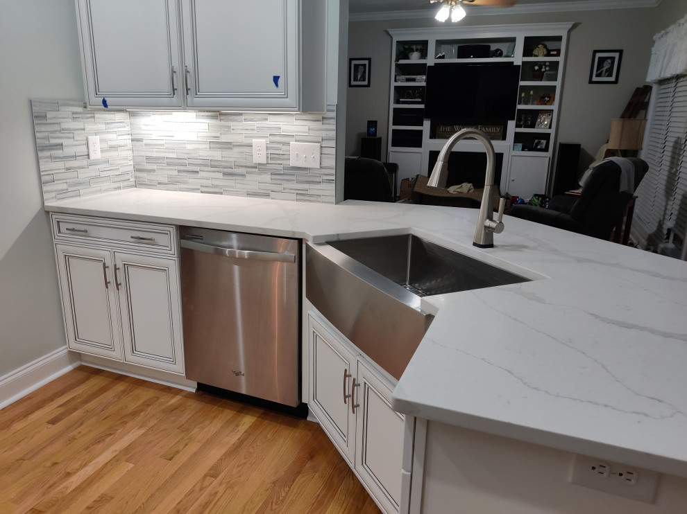 Example of a mid-sized medium tone wood floor kitchen design in Charlotte with a single-bowl sink, shaker cabinets, white cabinets, quartzite countertops, gray backsplash, glass tile backsplash, stainless steel appliances and white countertops
