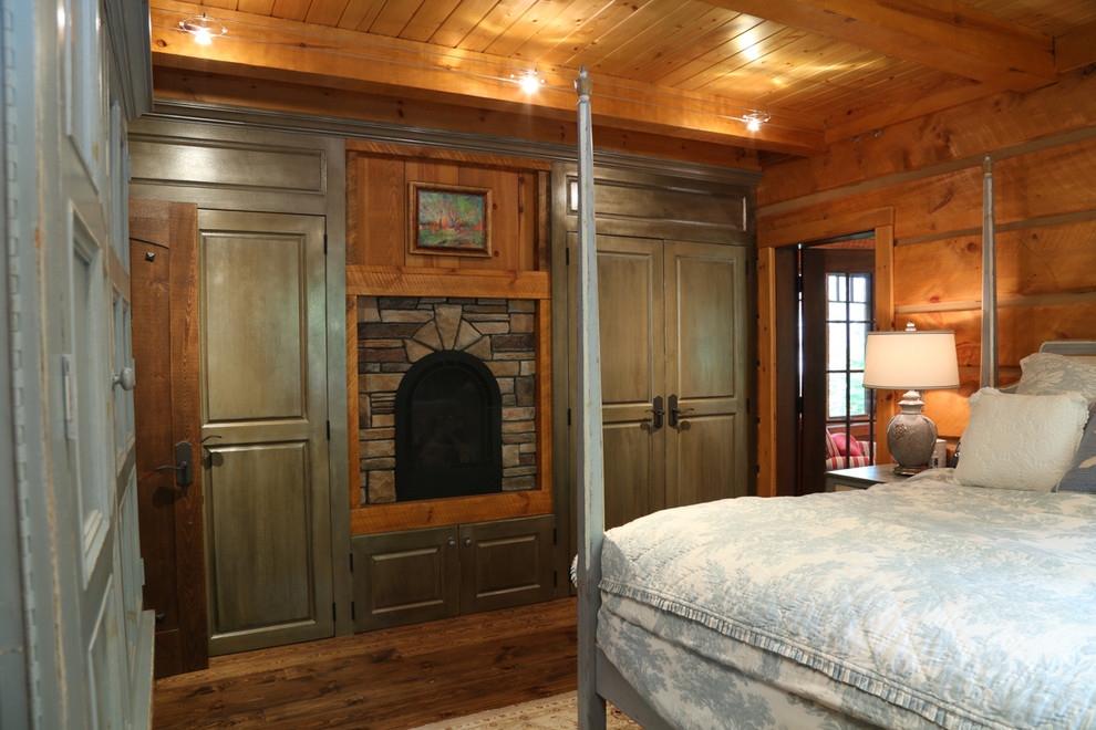 Mid-sized arts and crafts master bedroom in Toronto with brown walls, medium hardwood floors, a standard fireplace and a stone fireplace surround.