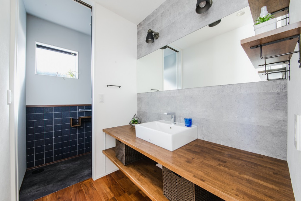 Cette photo montre un WC et toilettes industriel avec des portes de placard blanches, un mur gris, parquet foncé, un sol marron, un plan de toilette marron et meuble-lavabo encastré.