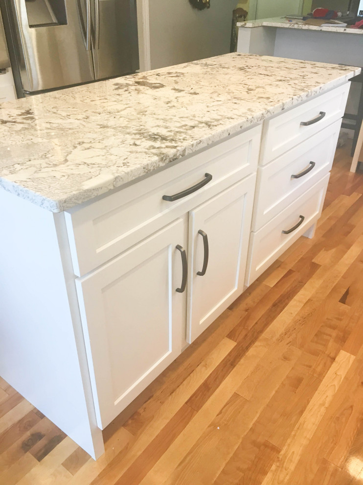 Eat-in kitchen - mid-sized transitional u-shaped medium tone wood floor and brown floor eat-in kitchen idea with recessed-panel cabinets, white cabinets, granite countertops, stainless steel appliances, an island and multicolored countertops