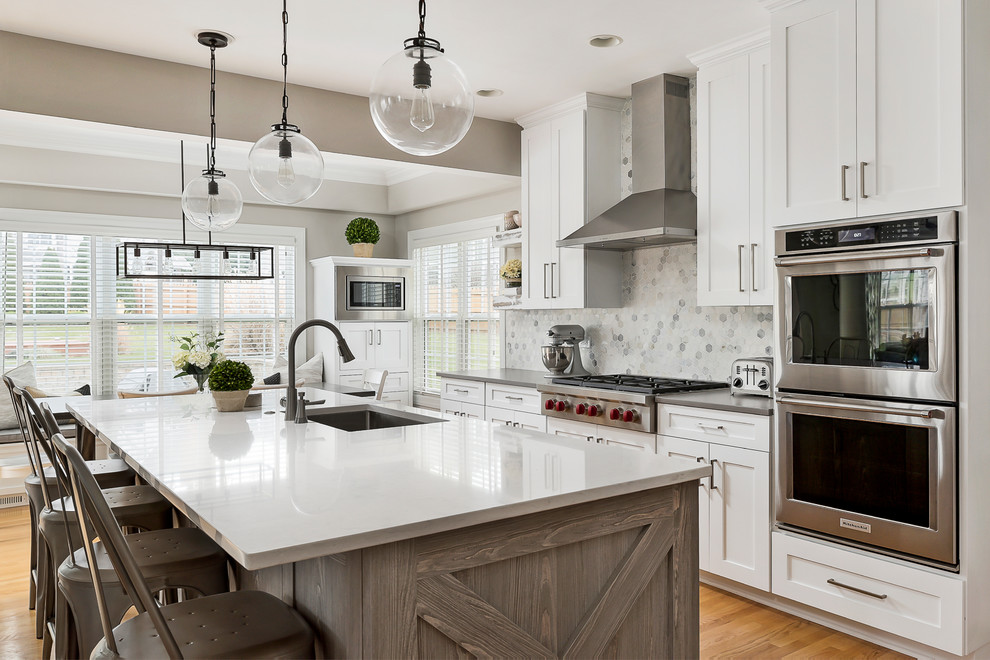 Large transitional light wood floor open concept kitchen photo in Chicago with an undermount sink, shaker cabinets, white cabinets, quartz countertops, gray backsplash, marble backsplash, stainless steel appliances and an island