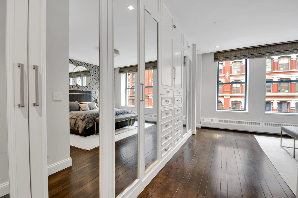 Inspiration for a large traditional gender-neutral built-in wardrobe in New York with raised-panel cabinets, white cabinets, dark hardwood floors and brown floor.