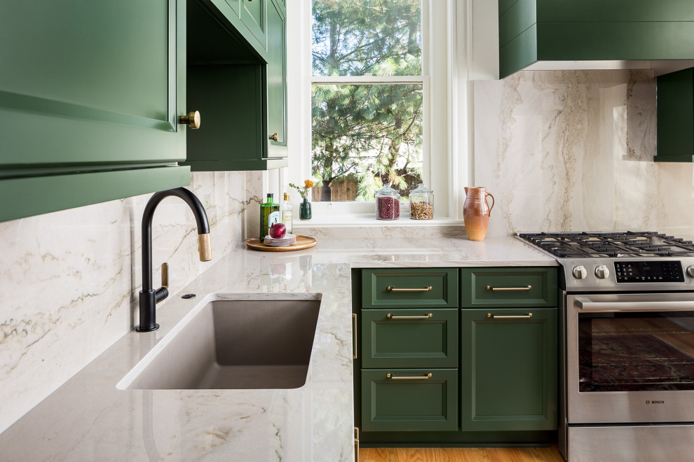 Small transitional l-shaped eat-in kitchen in Louisville with a single-bowl sink, recessed-panel cabinets, green cabinets, quartzite benchtops, grey splashback, stone slab splashback, stainless steel appliances, medium hardwood floors, a peninsula and grey benchtop.