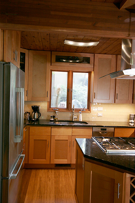 Eat-in kitchen - small transitional l-shaped porcelain tile eat-in kitchen idea with shaker cabinets, light wood cabinets, granite countertops, beige backsplash, glass tile backsplash, stainless steel appliances and a peninsula