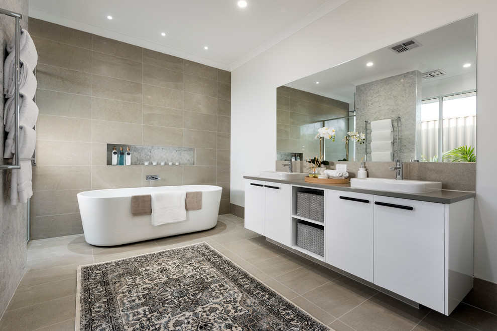 This is an example of a large transitional master bathroom in Perth with flat-panel cabinets, white cabinets, a freestanding tub, a corner shower, a one-piece toilet, brown tile, porcelain tile, white walls, porcelain floors, a drop-in sink, engineered quartz benchtops, beige floor and a hinged shower door.