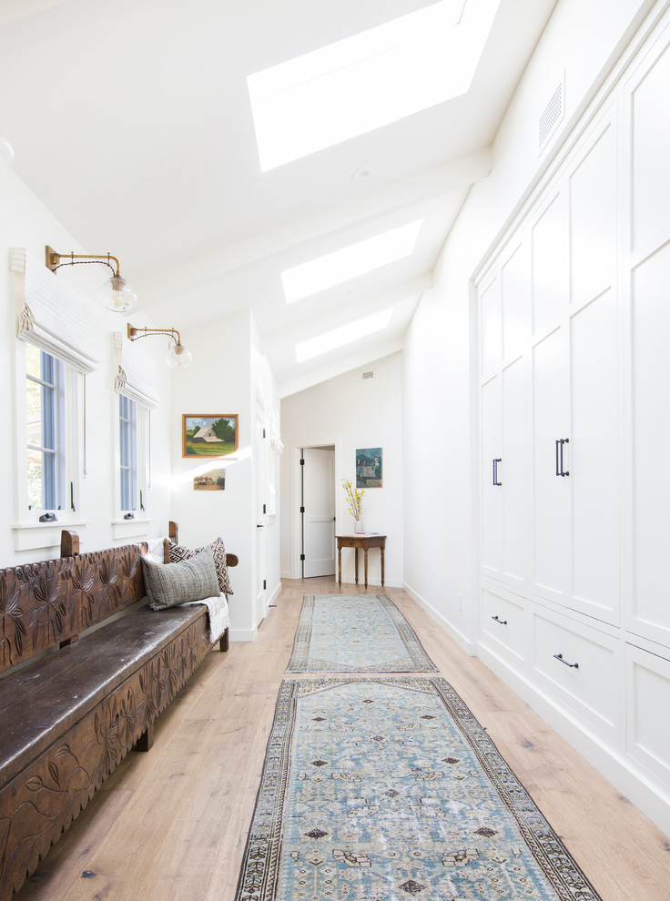 Photo of a beach style hallway in Los Angeles with white walls, light hardwood floors and beige floor.