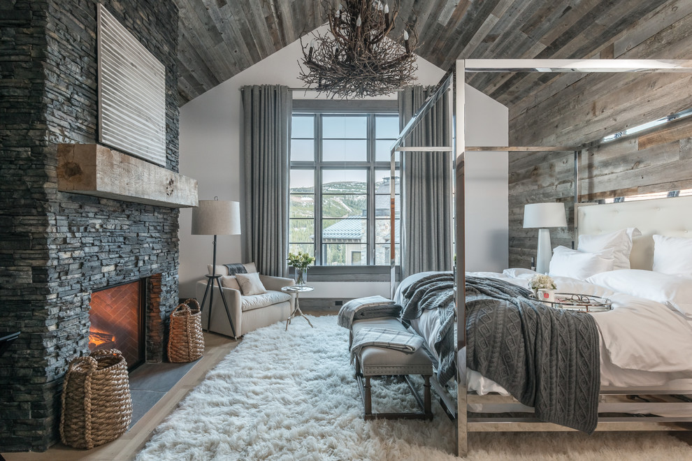 Large country master bedroom in Other with white walls, light hardwood floors, a standard fireplace, a stone fireplace surround and beige floor.