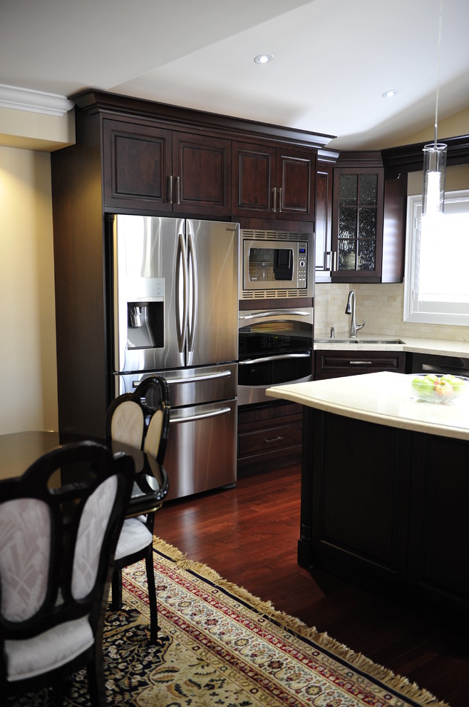Eat-in kitchen - mid-sized transitional u-shaped eat-in kitchen idea in Toronto with a double-bowl sink, raised-panel cabinets, dark wood cabinets, quartz countertops, multicolored backsplash, matchstick tile backsplash, stainless steel appliances and a peninsula