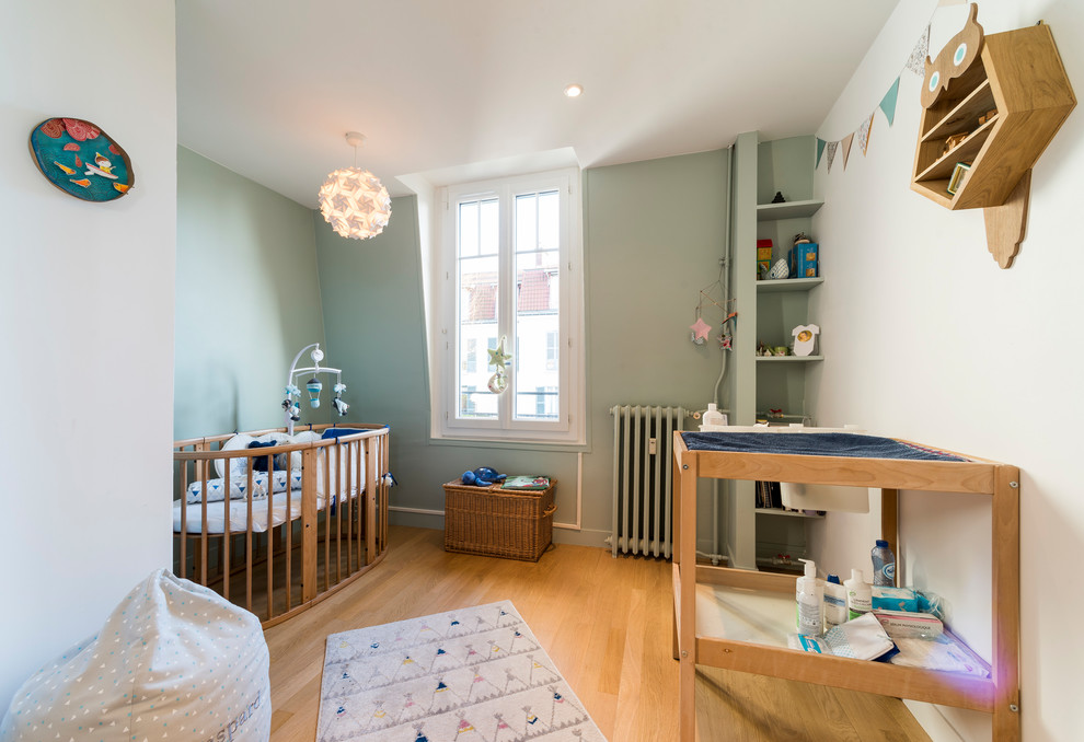 Traditional nursery in Paris with green walls, light hardwood floors and beige floor.