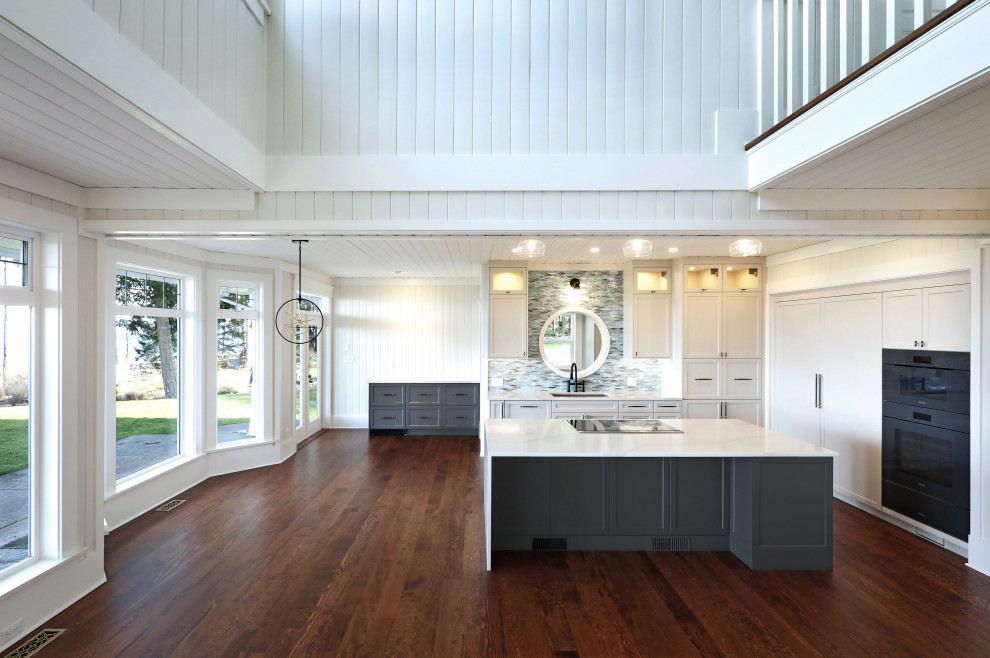 Foto på ett mellanstort maritimt kök, med en dubbel diskho, skåp i shakerstil, bänkskiva i kvarts, blått stänkskydd, stänkskydd i glaskakel, integrerade vitvaror, mellanmörkt trägolv, en köksö och brunt golv