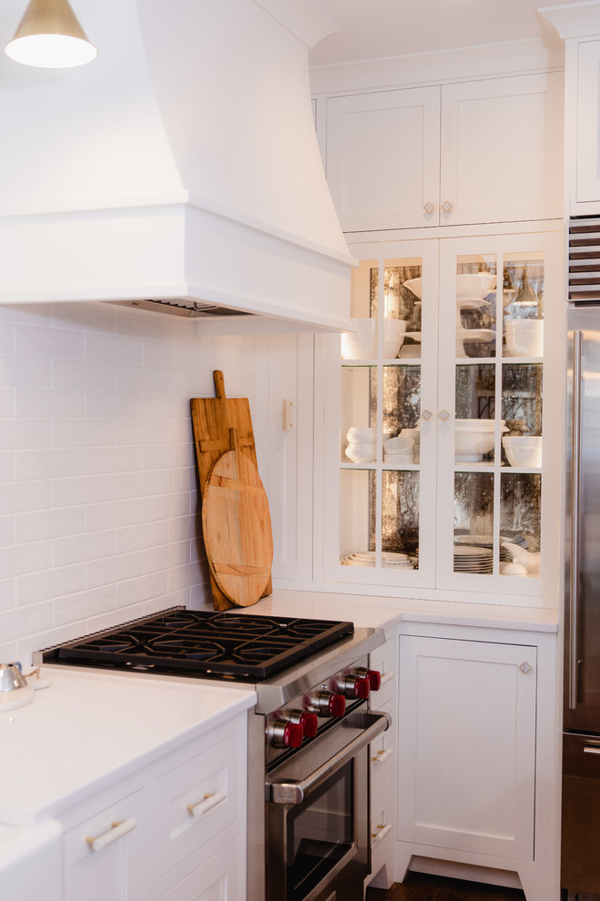 Small transitional l-shaped eat-in kitchen in Baltimore with a farmhouse sink, shaker cabinets, white cabinets, quartz benchtops, white splashback, cement tile splashback, stainless steel appliances, dark hardwood floors, with island, brown floor and white benchtop.