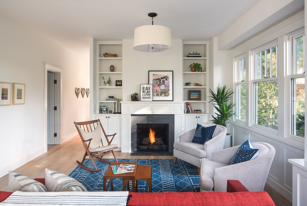 This is an example of a transitional living room in San Francisco with white walls, light hardwood floors, a standard fireplace and beige floor.