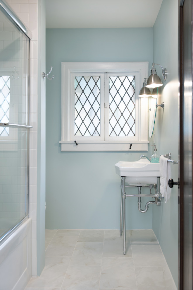 Inspiration for a small traditional bathroom in Kansas City with white cabinets, an alcove tub, a shower/bathtub combo, blue walls, porcelain floors, a console sink, white floor, a sliding shower screen and a single vanity.