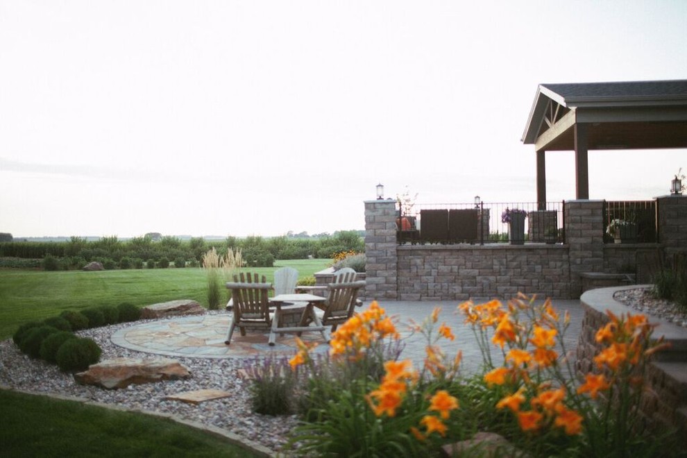 Example of a mountain style backyard gravel patio design with a fire pit