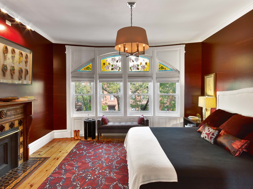 Design ideas for a traditional master bedroom in New York with red walls, light hardwood floors, a standard fireplace, a tile fireplace surround and beige floor.