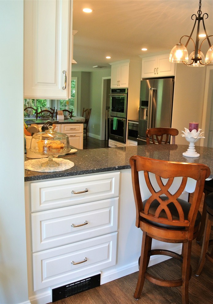Eat-in kitchen - transitional light wood floor eat-in kitchen idea in Boston with an undermount sink, raised-panel cabinets, white cabinets, granite countertops, white backsplash, subway tile backsplash and stainless steel appliances