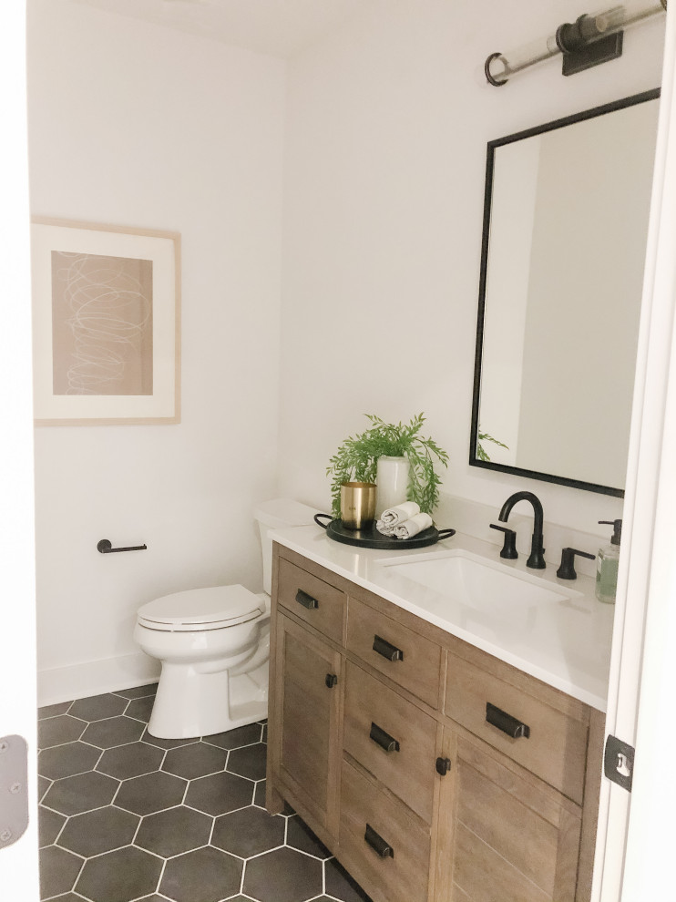 Transitional powder room in Cincinnati with a one-piece toilet, white walls, ceramic floors, an undermount sink, marble benchtops, black floor, white benchtops and a freestanding vanity.