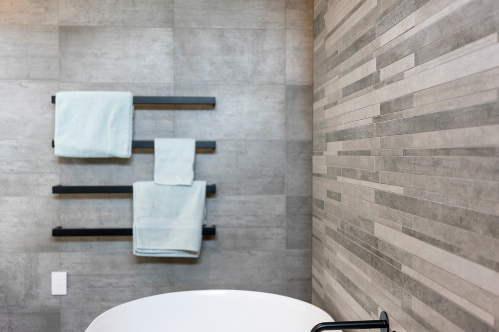 Photo of a mid-sized modern 3/4 wet room bathroom in Christchurch with a freestanding tub, gray tile, porcelain tile, porcelain floors, grey floor and an open shower.
