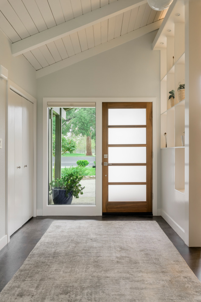Diseño de distribuidor actual grande con paredes grises, suelo de cemento, puerta simple, puerta de madera en tonos medios, suelo gris y machihembrado
