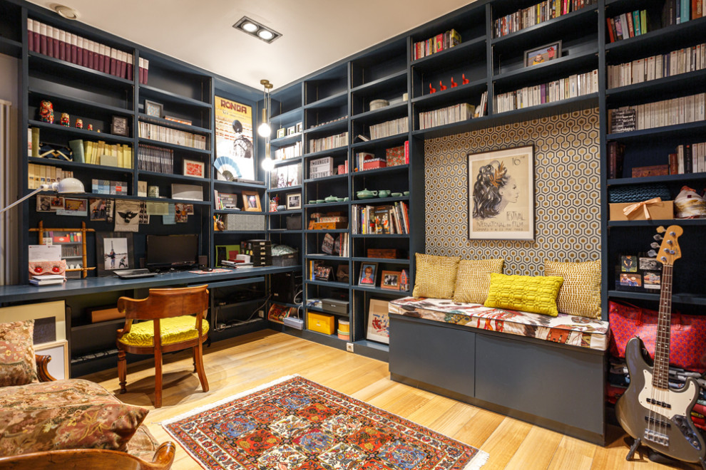 Photo of a mid-sized eclectic home office in Paris with a library, blue walls, light hardwood floors, no fireplace, a built-in desk and beige floor.