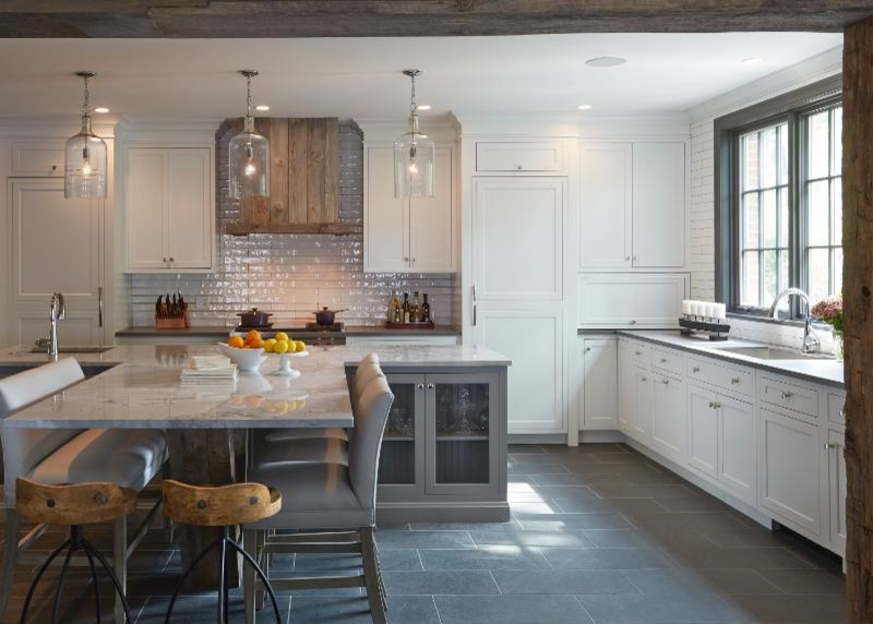 Inspiration for a mid-sized country eat-in kitchen in Chicago with a drop-in sink, recessed-panel cabinets, white cabinets, marble benchtops, white splashback, ceramic splashback, stainless steel appliances, porcelain floors, brown floor and with island.