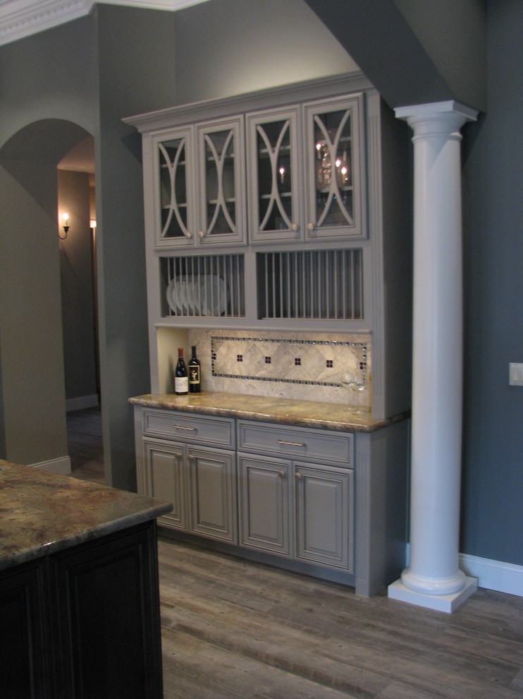 Inspiration for a huge transitional l-shaped porcelain tile open concept kitchen remodel in Phoenix with an undermount sink, raised-panel cabinets, gray cabinets, granite countertops, gray backsplash, stone tile backsplash, stainless steel appliances and an island