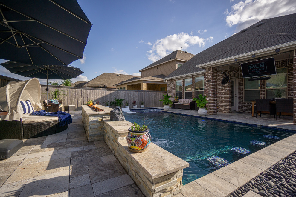 Immagine di una piscina tropicale rettangolare di medie dimensioni e dietro casa con pavimentazioni in pietra naturale