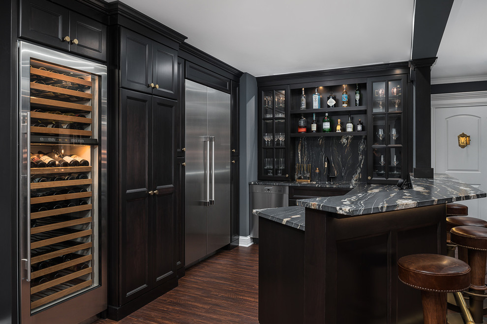 Large traditional u-shaped seated home bar in Chicago with dark hardwood floors, brown floor, glass-front cabinets, black cabinets, black splashback, stone slab splashback, black benchtop, an undermount sink and marble benchtops.