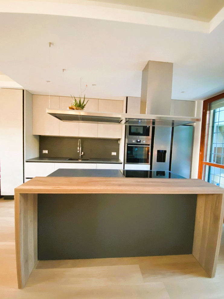 Design ideas for a mid-sized modern galley open plan kitchen in Rome with an undermount sink, flat-panel cabinets, white cabinets, quartz benchtops, black splashback, porcelain splashback, stainless steel appliances, light hardwood floors, with island, yellow floor, black benchtop and recessed.