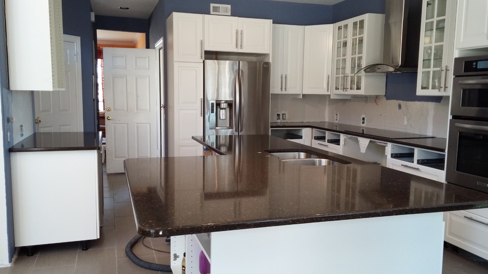 Large trendy u-shaped ceramic tile open concept kitchen photo in Austin with an undermount sink, glass-front cabinets, white cabinets, quartz countertops, stainless steel appliances, blue walls and an island