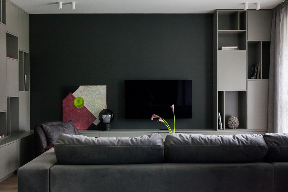 На фото: гостиная комната среднего размера в современном стиле с с книжными шкафами и полками, черными стенами, паркетным полом среднего тона и телевизором на стене с