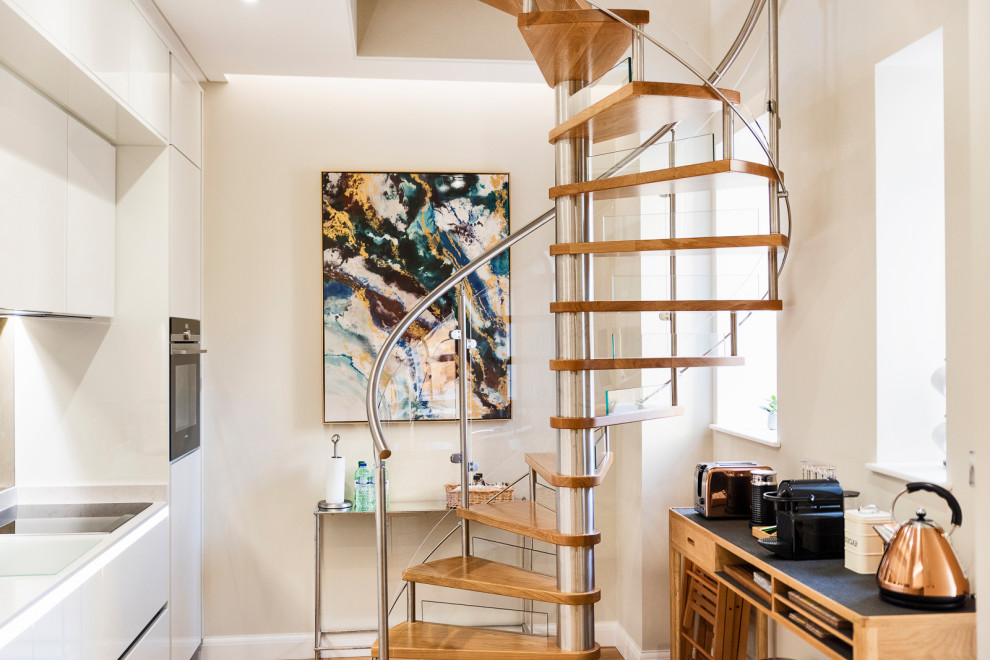 Small modern wood spiral staircase in Other with glass risers and mixed railing.