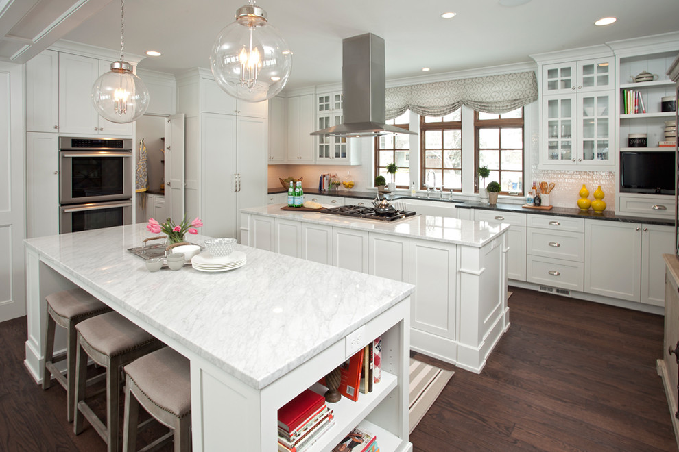 Inspiration for a large transitional kitchen in Minneapolis with a farmhouse sink, shaker cabinets, white cabinets, marble benchtops, white splashback, panelled appliances, dark hardwood floors and multiple islands.