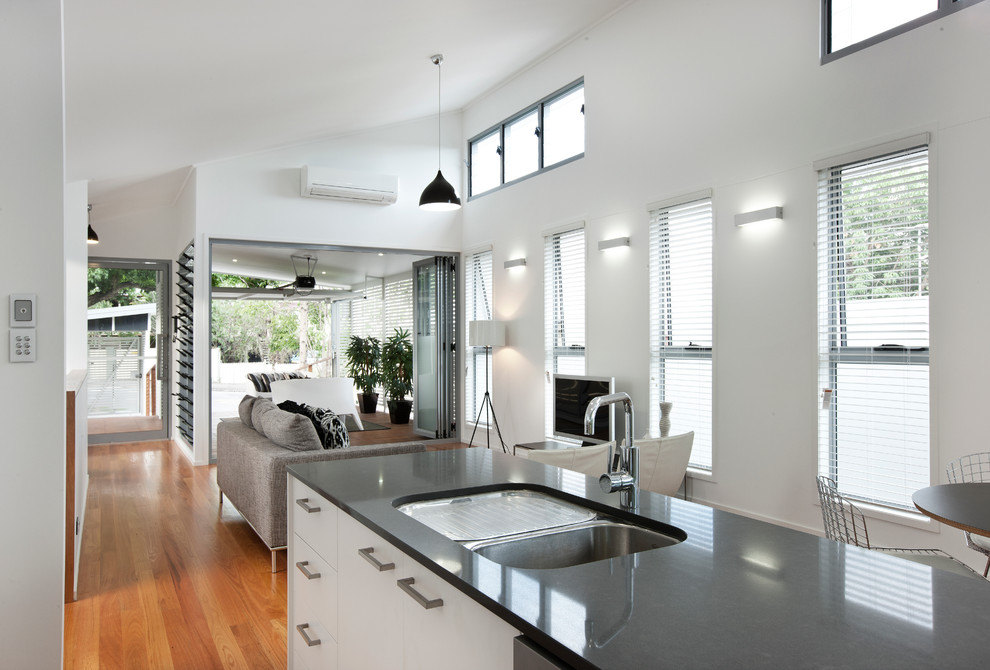 Design ideas for a small contemporary single-wall open plan kitchen in Brisbane with stainless steel appliances, with island, an undermount sink, flat-panel cabinets, white cabinets, black splashback, matchstick tile splashback and medium hardwood floors.