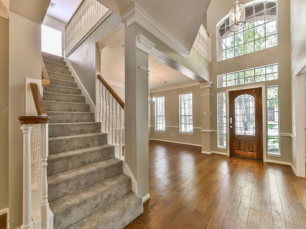 Foyer - mid-sized transitional medium tone wood floor and orange floor foyer idea in Houston with beige walls and a medium wood front door