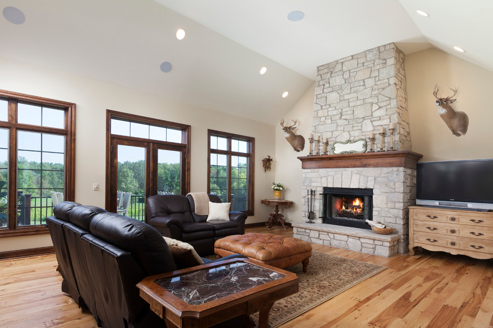 Photo of a large traditional open concept family room in Milwaukee with beige walls, light hardwood floors, a standard fireplace, a stone fireplace surround and a freestanding tv.