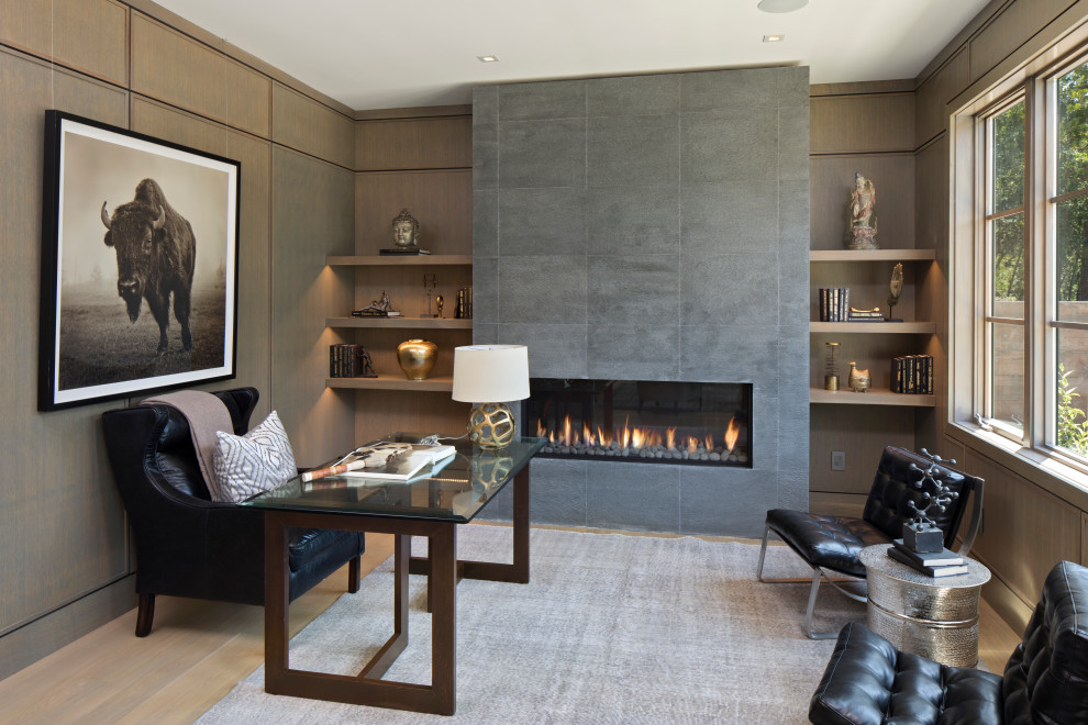Example of a transitional freestanding desk medium tone wood floor, brown floor and wall paneling home office design in San Francisco with black walls and a ribbon fireplace