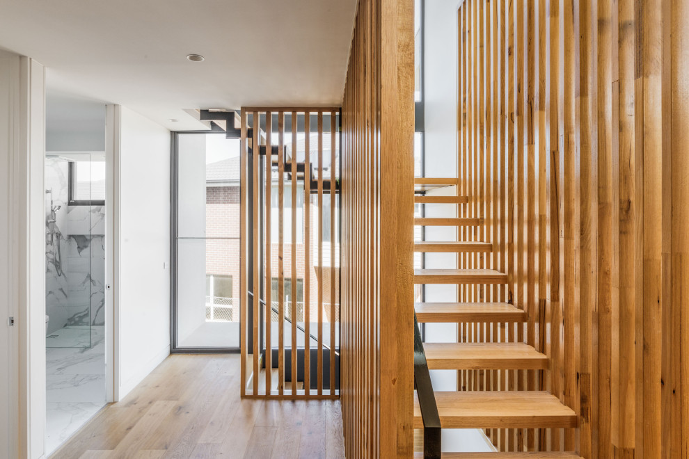 Diseño de escalera suspendida contemporánea grande con escalones de madera, barandilla de metal y madera
