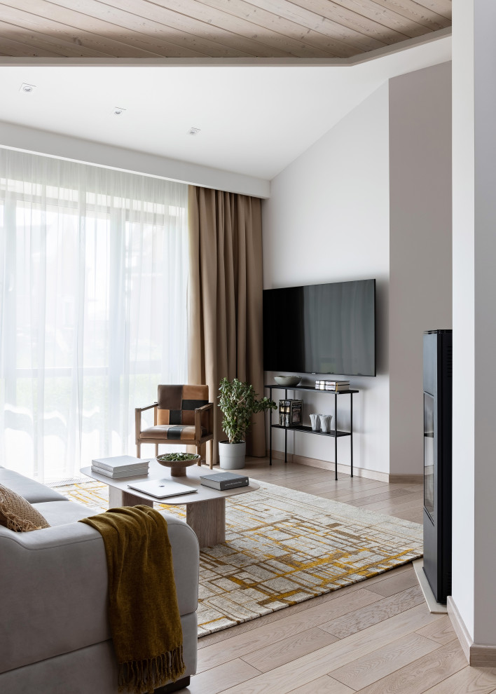 Идея дизайна: гостиная комната среднего размера в современном стиле с белыми стенами, паркетным полом среднего тона, печью-буржуйкой, фасадом камина из металла, телевизором на стене, коричневым полом и акцентной стеной