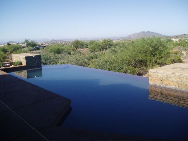 Mid-sized backyard brick and rectangular infinity pool photo in Phoenix