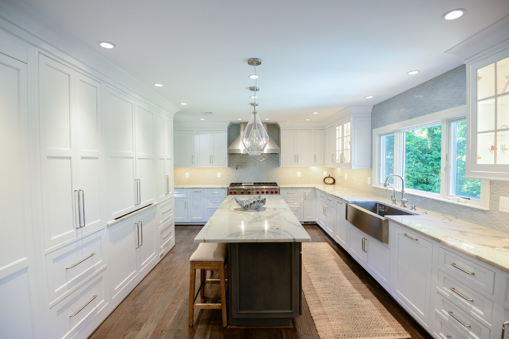 Example of a large transitional u-shaped medium tone wood floor and brown floor eat-in kitchen design in DC Metro with a farmhouse sink, recessed-panel cabinets, white cabinets, marble countertops, stainless steel appliances, an island, gray backsplash and porcelain backsplash