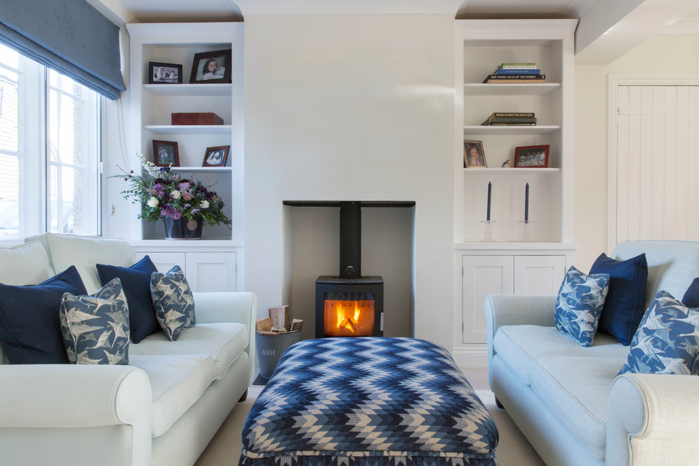 This is an example of a small beach style living room in Hampshire with beige walls, carpet and a wood stove.