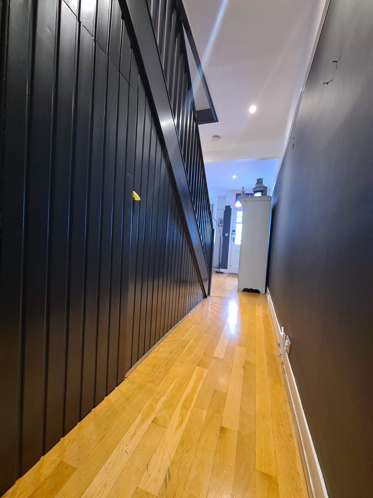 На фото: огромный коридор в классическом стиле с белыми стенами, деревянным полом, черным полом и многоуровневым потолком