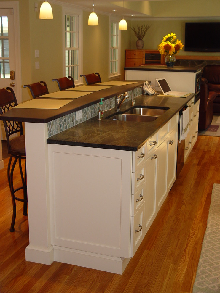 Example of a transitional kitchen design in Boston with an undermount sink, recessed-panel cabinets, white cabinets, granite countertops, black appliances and an island