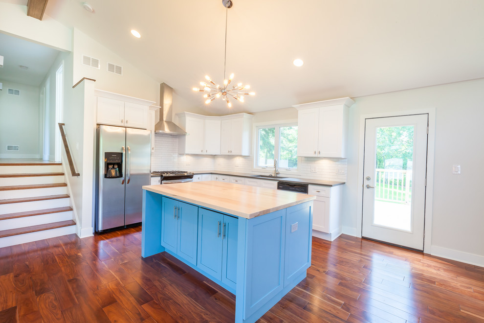 Design ideas for a mid-sized midcentury l-shaped open plan kitchen in Chicago with an undermount sink, shaker cabinets, white cabinets, wood benchtops, white splashback, subway tile splashback, stainless steel appliances, dark hardwood floors and with island.